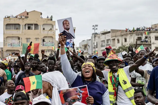 A supporter of Ousmane Sonko dances holding his portrait at a rally in Dakar